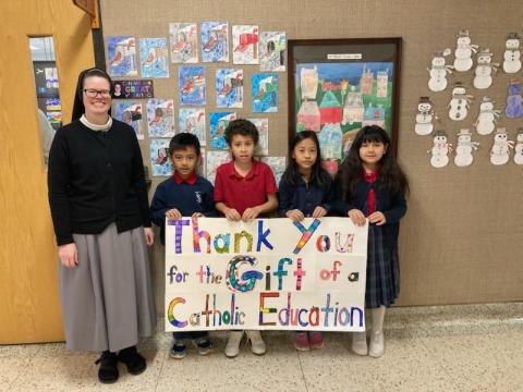 Students and sister (left) holding up a sign that reads, "Thank You for the Gift of Catholic Education."
