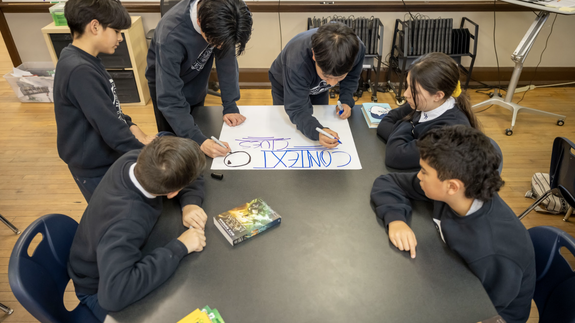 Students in a circle writing on a poster